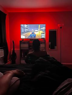 a person sitting on a bed in front of a flat screen tv playing video games