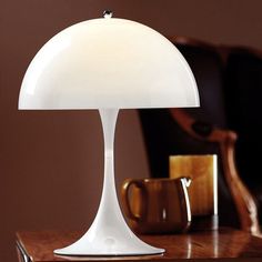 a white table lamp sitting on top of a wooden desk next to a brown chair