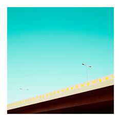 two street lights on the side of a bridge over looking water and blue sky in the background