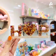 a person holding up the word love spelled out with candies in front of a store display