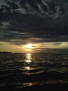 the sun is setting over the ocean with clouds in the sky and water below it