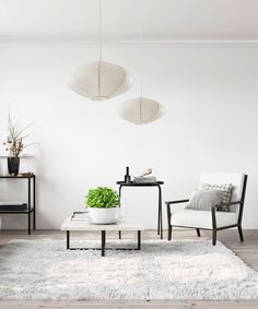 a living room with two chairs and a coffee table in front of a white wall