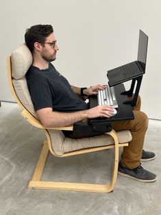 a man sitting in a chair with a laptop on his lap and holding the keyboard