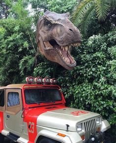 a dinosaur head hanging over the top of a jeep