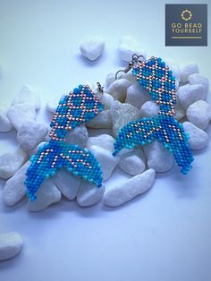 the earrings are made out of beads and have been placed on some rocks with stones around them