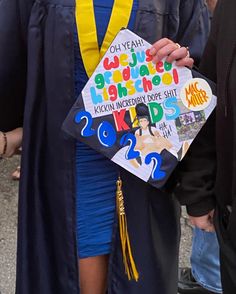 a person wearing a graduation gown and holding a sign