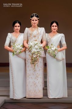 three women in white dresses standing next to each other with flowers on their bouquets