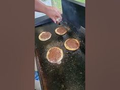 four pizzas being cooked on an outdoor grill with someone using a spatula to stir them