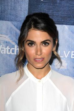 a close up of a person wearing a white shirt and hair in a pony tail