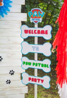 a welcome sign for paw patrol party in front of a wooden structure with red, white and blue streamers