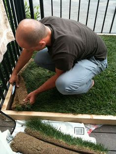 a man kneeling down in front of a wooden box with grass growing out of it