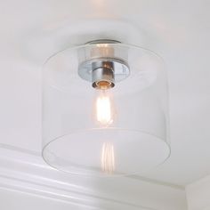 a clear glass light fixture hanging from the ceiling in a room with white walls and ceilings