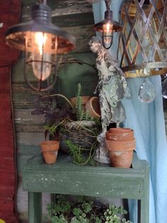 some potted plants are sitting on a table with a light hanging over it and other pots