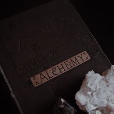 an old book with the word alchemy written on it next to some ice cubes