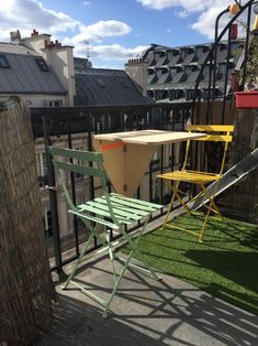 two lawn chairs sitting on top of a wooden deck next to a green table and chair