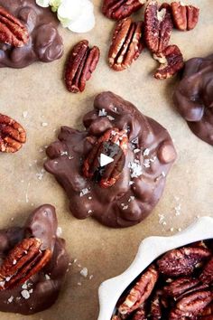 chocolate covered pecans with nuts and sea salt on the top, surrounded by other pecans