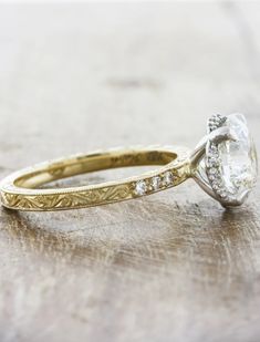 a close up of a diamond ring on a wooden surface