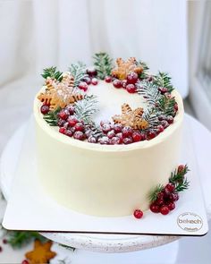 a white cake with frosting and cranberries is on a platter next to other holiday decorations