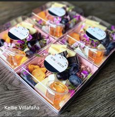 four plastic containers filled with assorted cheeses and fruit on top of a wooden table