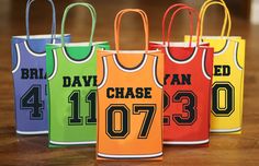 four colorful basketball jersey bags sitting on top of a wooden table next to each other