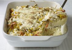 a casserole dish filled with rice, vegetables and meat in a white baking dish