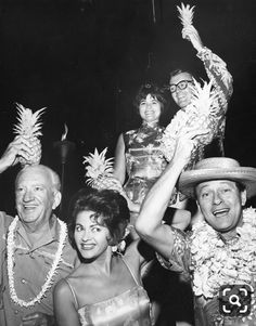 a group of people standing next to each other in front of a man wearing a hat