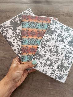 a person's hand holding four different patterned papers