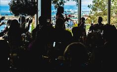 a group of people sitting in front of a window with the view of a city