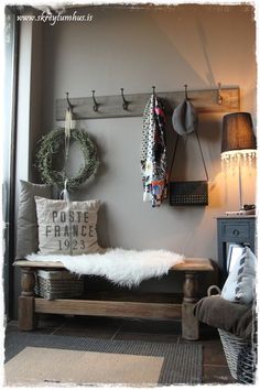 a bench with pillows and wreaths hanging on the wall next to coat hooks,