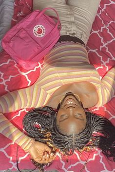 a woman laying on top of a bed next to a pink bag and purses