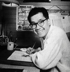 a black and white photo of a man in glasses writing