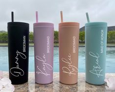 four different colored tumbles with their names on them next to a pool and flowers