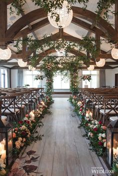 an indoor wedding venue decorated with greenery and flowers, candles and chandeliers