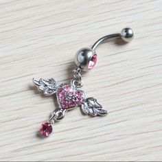 a pink heart and angel belly ring on a wooden table