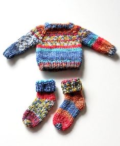 a knitted sweater, mittens and booties on a white surface