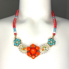 "Orange is one of my favorite colors, and it is especially vibrant when paired with turquoise blue. This fun and funky bib necklace has 5 vintage clip earrings set on a brass jewelry form to create a one of a kind statement necklace. Bright and colorful, but not overpowering, this bib hangs from a beaded necklace of orange glass beads mixed with vintage turquoise colored tube beads. The stars of this show are the flower cameos on either side of center. Very 1970s, Holly Hobby-esque. Bib is 3.75\ Retro Beaded Jewelry For Gifts, Retro Beaded Jewelry Gift, Retro Beaded Jewelry As Gift, Multicolor Retro Jewelry For Vintage Collection, Multicolor Nickel-free Retro Jewelry, Retro Multicolor Nickel-free Jewelry, Vintage Multicolor Czech Glass Jewelry, Retro Vintage Charm Jewelry For Jewelry Making, Vintage Turquoise Jewelry With Colorful Beads