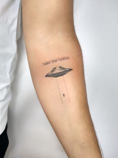 a man with a tattoo on his arm that says take me home and an alien spaceship is flying through the sky