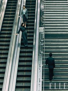 two people are walking up an escalator and another person is standing next to them