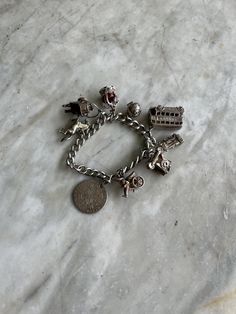 Vintage sterling silver charm bracelet. Made in the UK in the 1950s. The bracelet has exceptional charms:an  18th century English silver coin, a Chinese  man pulling a rickshaw, a vintage telephone  that opens, a locomotive, a London bus, a football, the British crown, a coal scuttle, and  a shire horse. There are 9 charms in total. The bracelet chain is 0.8 cm wide, and 19.5 cm  long.  It weighs 78 grams and is in excellent condition. Telephone Vintage, Shire Horse, Vintage Sterling Silver Charms, Chinese Man, Vintage Telephone, Sterling Silver Charm Bracelet, London Bus, Bracelet Chain, Silver Charm Bracelet