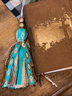 a book with a cross on it sitting on a table next to a tassel