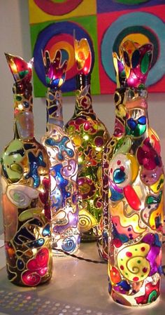 three colorful glass bottles sitting next to each other on top of a table in front of a painting