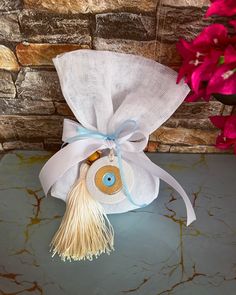 a white bag with a blue ribbon and an evil eye on it sitting on a table