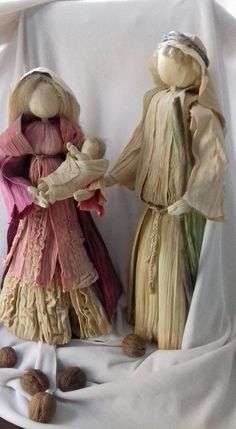 two figurines are standing next to each other on a white cloth covered surface