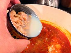 a person scooping food out of a pot with a ladle in their hand