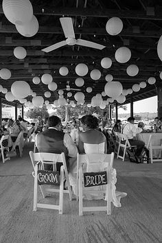 black and white photograph of two people sitting in chairs with paper lanterns hanging from the ceiling