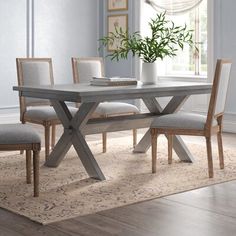 a dining room table with two chairs and a potted plant