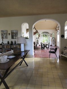 a living room filled with furniture and a book shelf next to a doorway that leads into a dining area