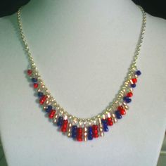 a necklace with red, white and blue beads is displayed on a mannequin