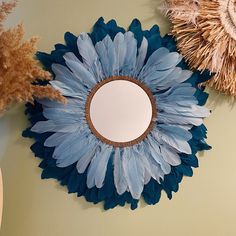 there are two mirrors on the wall with blue and brown feathers hanging above each mirror