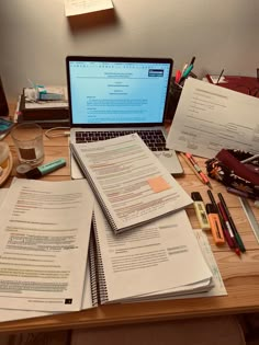 a laptop computer sitting on top of a wooden desk next to papers and pencils